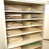 A cream-coloured metal cabinet with open doors. Two columns of specimens in manila folders sit on six shelves inside the cabinet. The ends of many paper sheets are visible inside the folders.