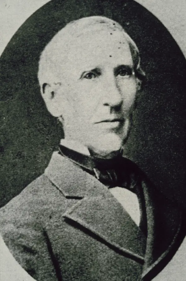 A black and white portrait photo of Sonder. He is wearing a grey suit jacket over a black cravat and white shirt.
